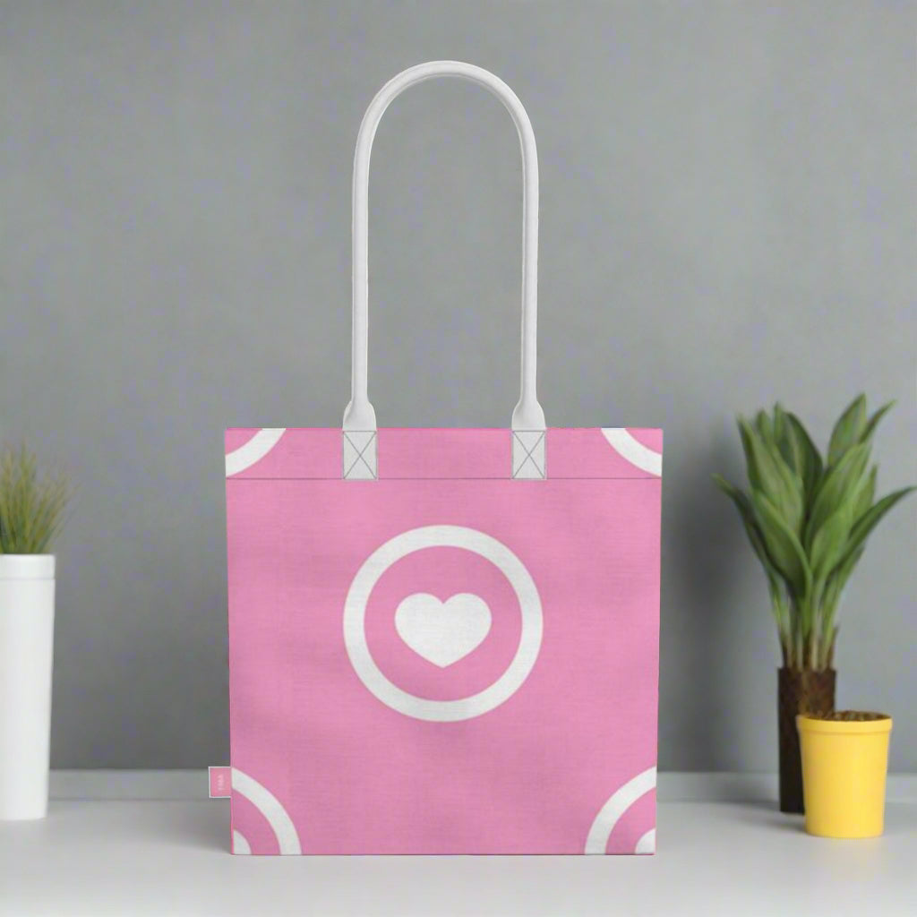Pink tote bag with white heart and circle design on a grey witha cactus