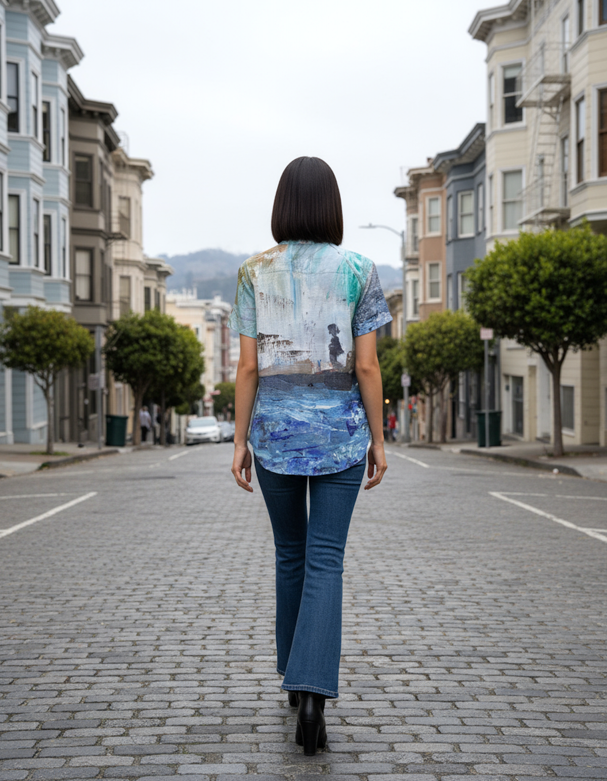 Woman walking down a street wearing a colorful shirt with a scenic print