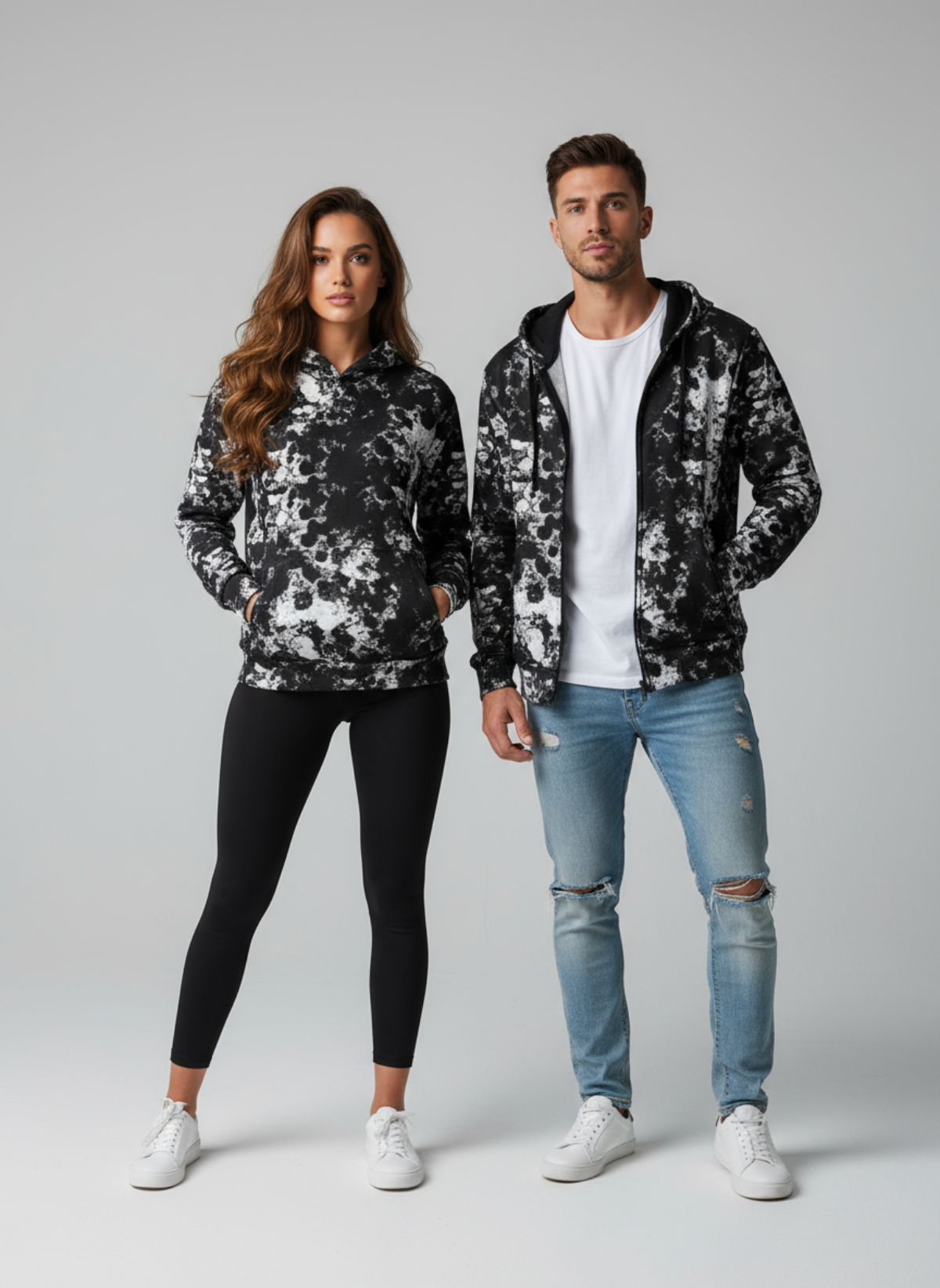 Two people wearing matching black and white floral hoodies on a gray background