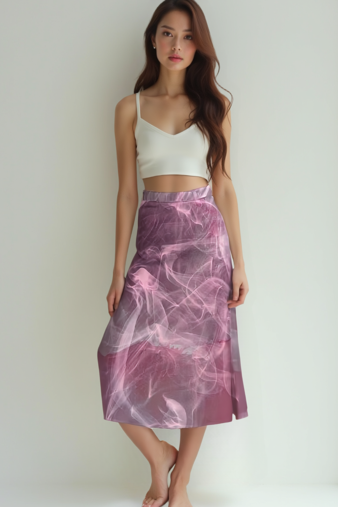 Woman wearing a white top and pink tie-dye skirt against a plain background