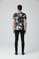 Person wearing a black and white patterned shirt on a plain background