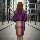 Person wearing a purple blouse and colorful striped skirt walking down a cobbled street.