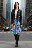 Woman walking on a city street wearing a black leather jacket, white top, and colorful skirt.