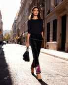 Woman walking down a city street wearing a black outfit with floral shoes.