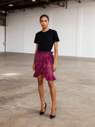 Woman wearing a black top and pink skirt in an indoor setting