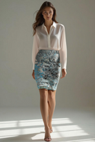 Woman wearing a white blouse and patterned skirt standing against a neutral background