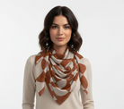 Woman wearing a patterned scarf on a plain background