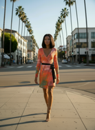 Woman in a colorful dress walking on a city street with palm trees in the background