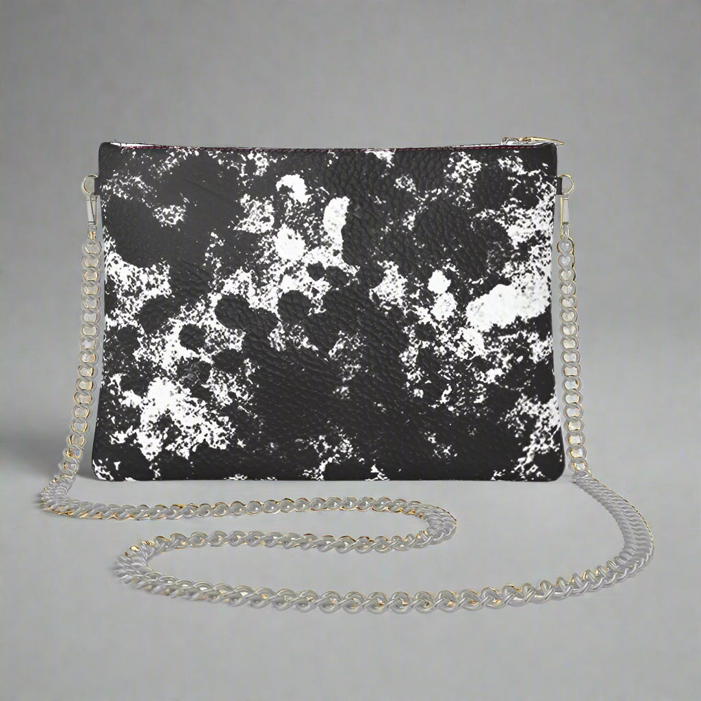A black and white camouflage Urban Decay crossbody bag with a silver chain strap.