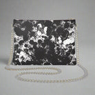 A black and white camouflage Urban Decay crossbody bag with a silver chain strap.