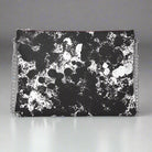 A black and white leather crossbody bag with a chain strap and a floral pattern.